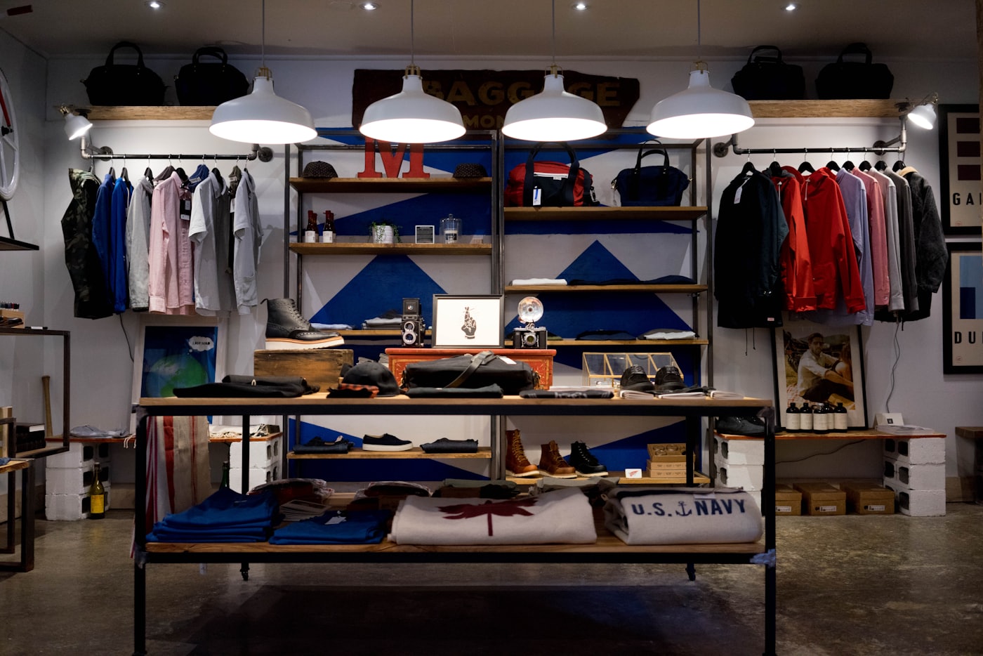 Interior de uma loja de roupas com araras, prateleiras e mesa de exposição